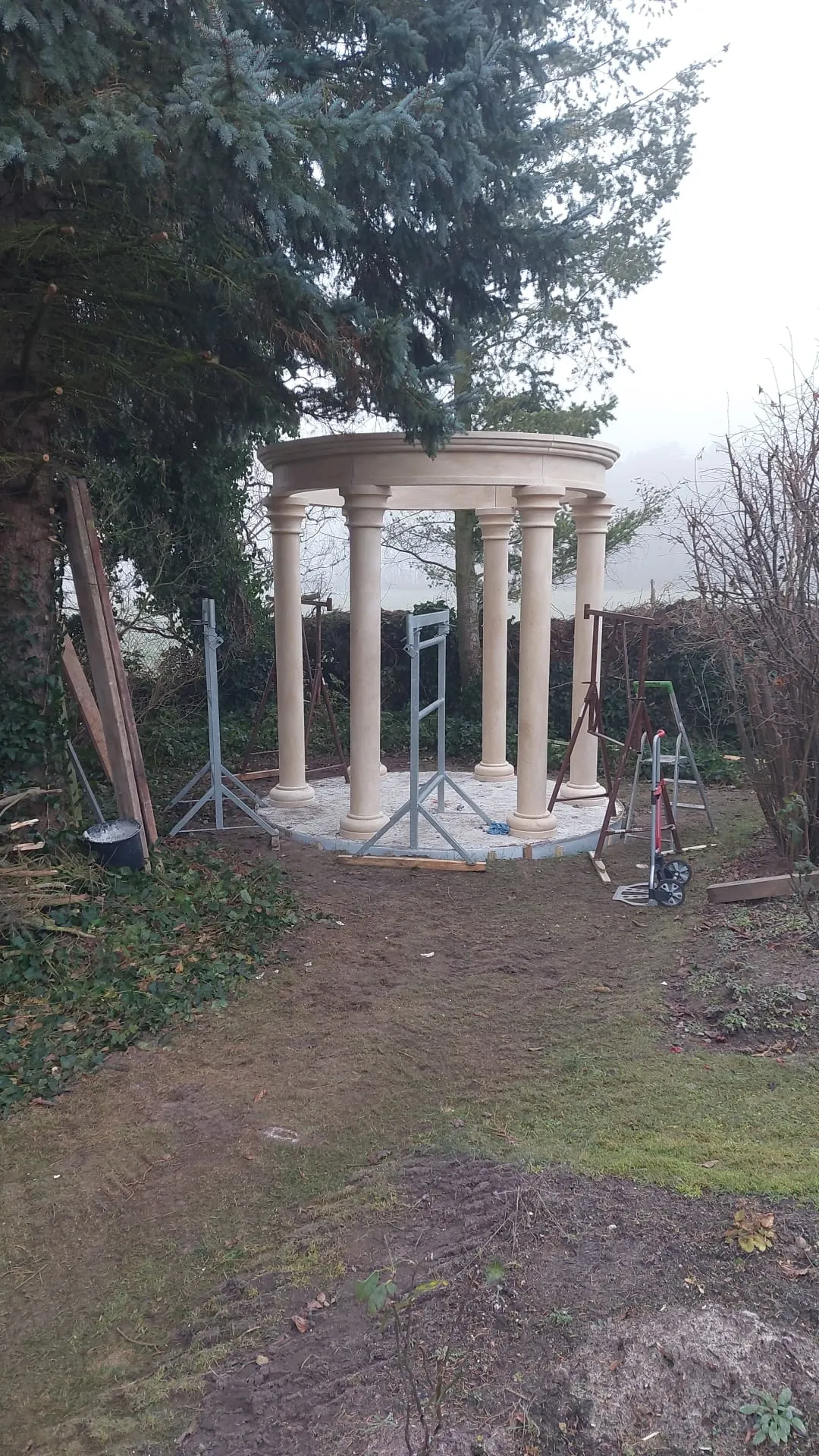 Sechs Sandsteinsäulen auf einem runden Fundament, im Rohbau abgestützt
