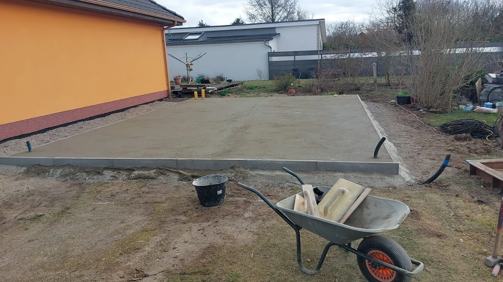 Frisch abgezogene Betonplatte mit Randeinfassung und verlegten Leerrohren